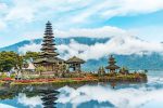 brown and green temple near body of water under blue and white cloudy sky during daytime