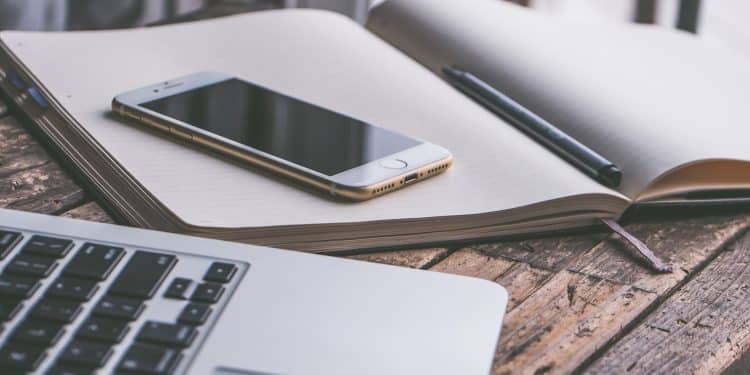 Gold Iphone 7 on Top of Book Beside Macbook