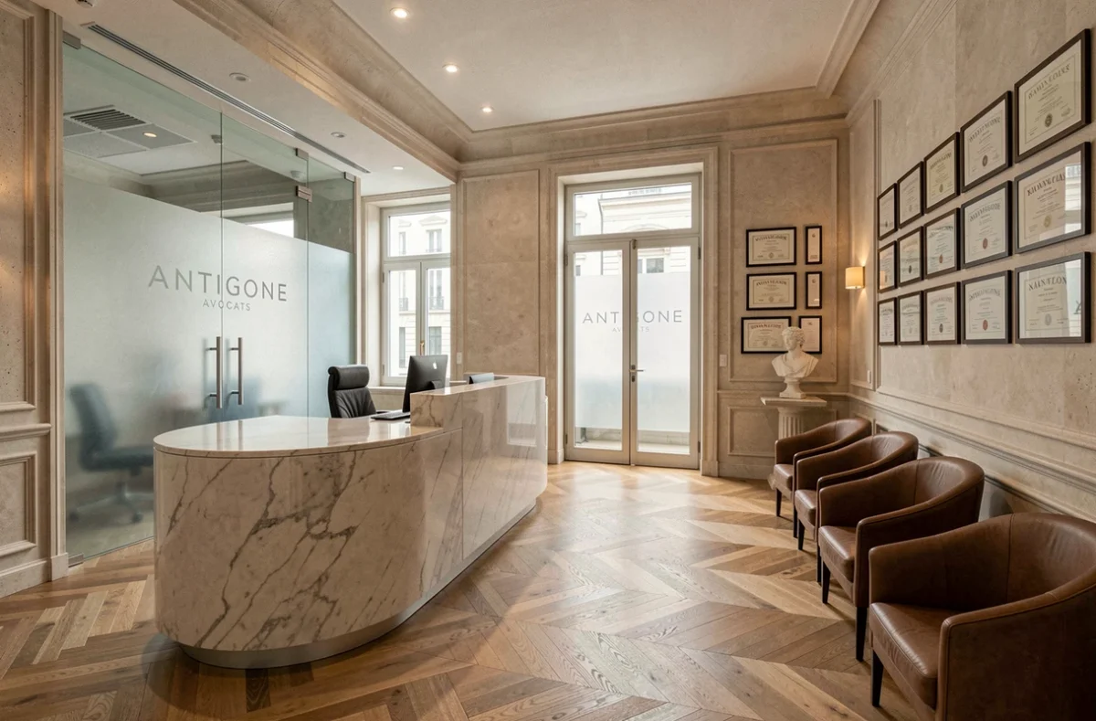 Réception moderne du cabinet Antigone Avocats à Nantes avec comptoir en marbre et fauteuils en cuir