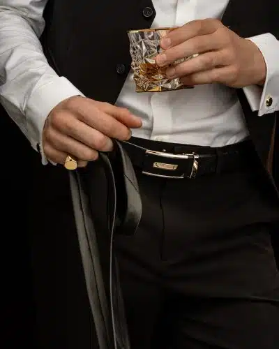 person in white dress shirt and black pants holding gold ring